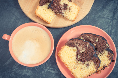 Fresh baked pieces of yeast dough with cocoa and chocolate icing, cup of coffee with milk. Delicious...