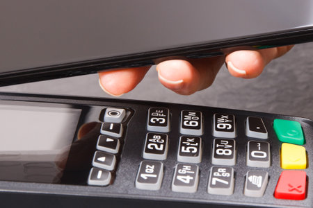 Hand of woman using payment terminal and smartphone to cashless paying. Finance and banking concept