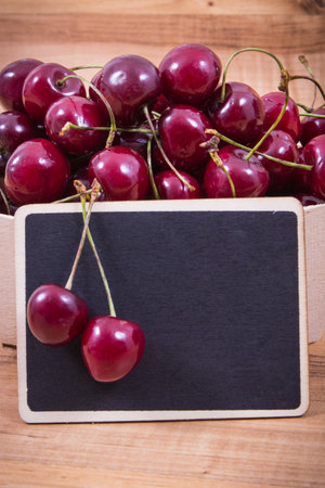 Fresh ripe juicy cherries in container. Dessert or snack. Copy space for text or inscription on black boardの写真素材