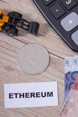 Ethereum coin, euro bills, miniature excavator and calculator. Symbol of cryptocurrency. International network payment. finance conceptの写真素材