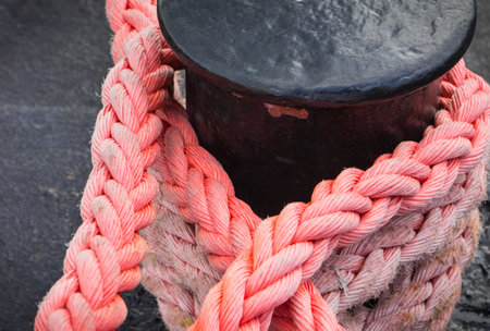 Thick rope and black mooring bollard. Detail and part of port. yachting