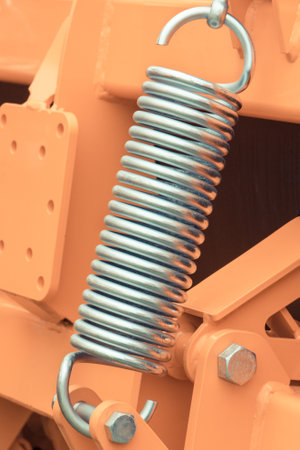 Silver hard spring made of steel. Detail and part of big industrial or agricultural machine....