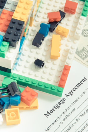 House under construction made of colorful toy blocks, dollars, mortgage agreement form. Subject of renting real estate and building homeの写真素材
