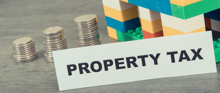 Inscription property tax with small house made of colorful toy blocks. Increasing real estate or luxury taxation. Tax paymentsの写真素材