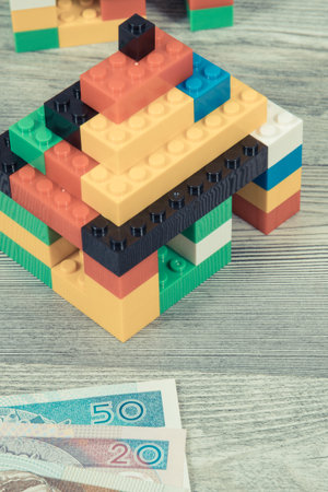 Small houses made of colorful toy blocks and Polish currency money. Subject of building home costs