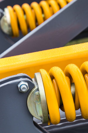 Yellow hard spring made of steel. Detail and part of big industrial or agricultural machine. Technologyの写真素材