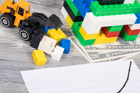 Small house made of colorful toy blocks, dollar banknotes and rising graph representing increase in...