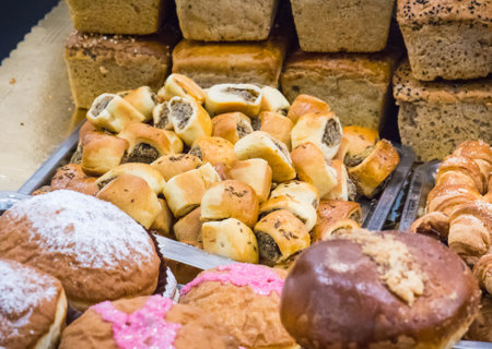 Fresh baked glazed donuts and other cookies on market stall or in grocery shop. Delicious crunchy dessertの写真素材