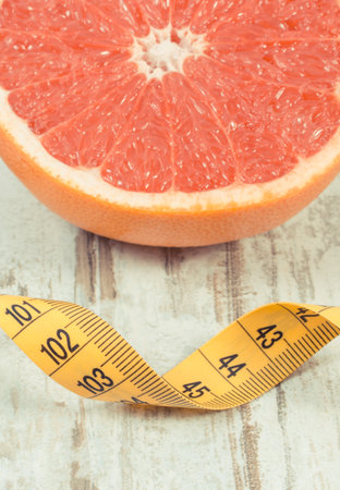 Fresh ripe grapefruit and tape measure on old rustic board. Fruits as a source of minerals and vitaminsの写真素材