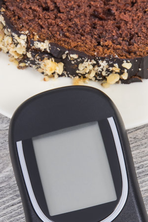 Glucometer using for measuring sugar level and sweet chocolate cake. Nutrition during diabetes conceptの写真素材