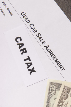 Inscription car tax, dollar banknotes and vehicle sales agreement. Sales, purchases and taxation of automobiles. Transportationの写真素材