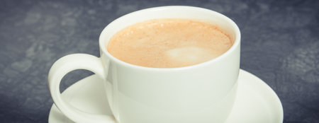 Cup of fresh prepared coffee with milk on dark background