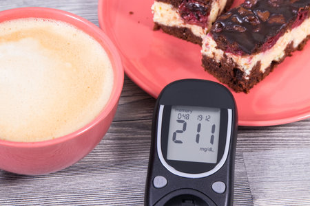 Glucometer using for measuring sugar level, pieces of fresh baked cheesecake with cherries and chocolate, cup of coffee with milk. Nutrition during diabetes conceptの写真素材