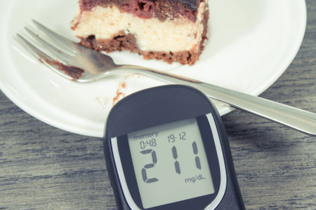 Glucometer with bad result of measurement sugar level and pieces of fresh baked cheesecake with cherries and chocolate. Healthy lifestyle and nutrition during diabetes conceptの写真素材