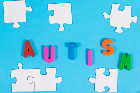 White and blue puzzle, inscription autism as symbol of Autism Spectrum Disorder. Autism Awareness Day conceptの写真素材