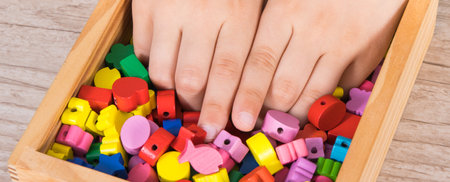 Hands of baby playing thread and wooden colorful beads used to making bracelets. Development of children motor skills, coordination, creativity and logical thinkingの写真素材