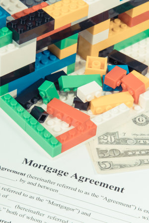 House under construction made of colorful toy blocks, dollar currencies, mortgage agreement form. Subject of renting real estate and building homeの写真素材