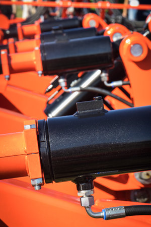 Black pistons or actuators in red pneumatic or hydraulic machine.