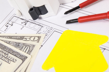Electrical components, work tools, yellow paper in shape of house and dollar banknotes. Electric...