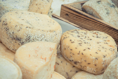 Blocks of fresh cheese with spices for sale on stall or in grocery shopの写真素材