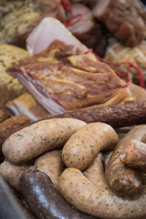 Fresh prepared smoked hams and sausages with spices on market stall or in grocery shop