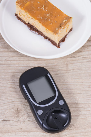 Glucometer using for measuring sugar level and sweet cheesecake. Nutrition during diabetes conceptの写真素材