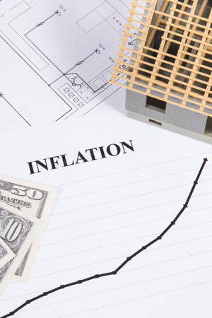 Inscription inflation, dollar currencies, small toy house under construction and electrical construction drawings. High prices of real estate, building or rent homeの写真素材