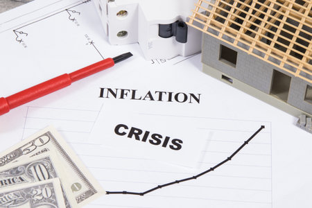 Electric fuse, screwdriver, small house under construction and currencies Dollar with inscriptions crisis and inflation. Concept of high prices of building homeの写真素材