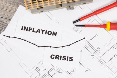 Inscriptions crisis and inflation, small house under construction on electrical diagrams of house. Concept of high prices of real estate, building or rent homeの写真素材