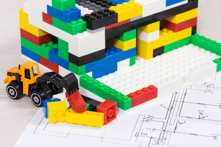 Electrical diagrams of house with miniature excavator and building under construction made of colorful toy blocks. Subject of building or renting homeの写真素材