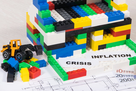 House under construction made of colorful toy blocks, money with housing plan. Concept of rising...