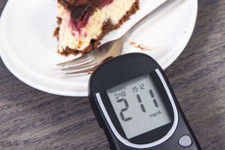 Glucometer with high result of measurement sugar level and pieces of fresh baked cheesecake with cherries and chocolate. Nutrition during diabetes conceptの写真素材