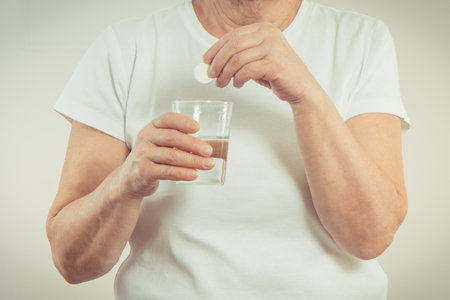 Elderly senior woman with effervescent tablet in hand. Vitamins or supplements. Treatment or strengthening immunity in old age. Health careの写真素材