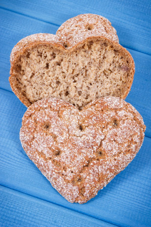 Fresh baked homemade wholegrain bread in shape of heart for breakfast. Blue boards background