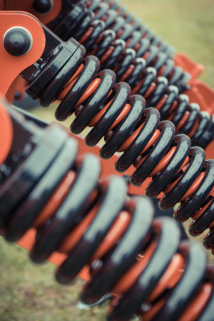 Black hard spring made of steel. Detail and part of big industrial or agricultural machine....