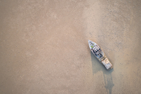 Big old fishing boat standing in the mud sea. Aerial view from flying droneの写真素材