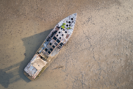 Big old fishing boat standing in the mud sea. Aerial view from flying droneの写真素材