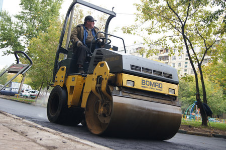 Packing of a new asphalt covering on road before an apartment house within the limits of the city...