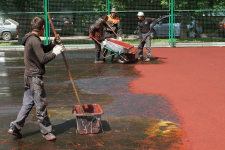06 06 2013 Moscow  Workers put a rubber polyurethane covering on the sports ground 