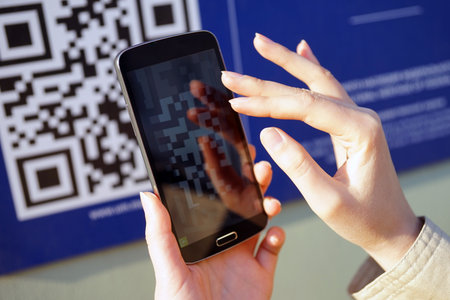 The girl scans QR code with mobile smart phone.の写真素材