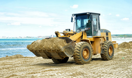 Tractor on the sea beach, spreads new sand.