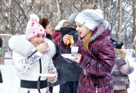MOSCOW, RUSSIA - February 18, 2012: Children eat pancakes. Celebrating carnival Maslenitsa in Moscow.のeditorial素材