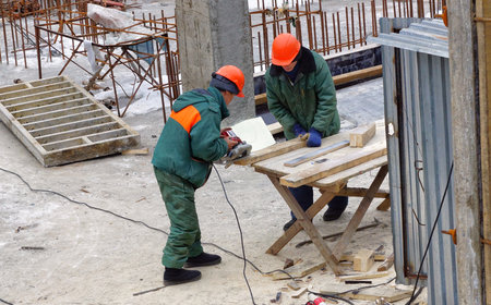 MOSCOW, RUSSIA - February16, 2013: Workers in helmets and uniforms saw the boards with a circular saw. Reconstruction of the Church of the Transfiguration of the Lord on the Transfiguration Square in Moscow.のeditorial素材