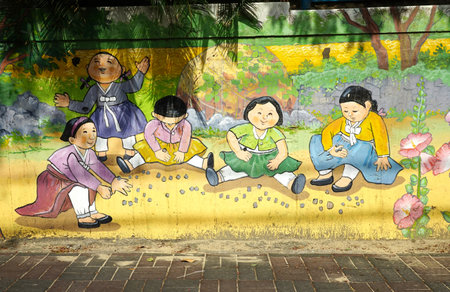 Jeju island, South Korea - April 2018: Korean girls are playing with stones. Retro drawings from the life of old-school students on the wall of the school in Jeju.のeditorial素材