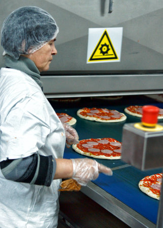 MOSCOW, RUSSIA - JANUARY , 2012: A woman at the conveyor with pizza. Factory of bakery products in Moscow.のeditorial素材