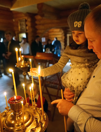 MOSCOW, RUSSIA - May 2016: A girl in the arms of her father, put candles in an Orthodox church.のeditorial素材
