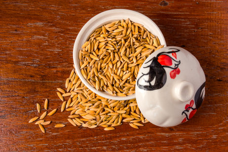 Paddy seeds in a cup of white coating on the wooden floor.の写真素材