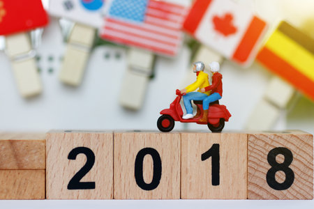 Miniature traveler with motorcycle on the wood block with number 2018. Travel  concept.
