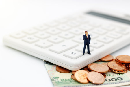 Miniature people, businessman standing with calculator and coins money,  tax, financial and business concept.の写真素材