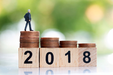 Miniature businessman standing on step of coin money with block number 2018. Finance and growth in business conceptの写真素材